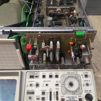 Image showing part of the front panel of the Hameg HM1005 analog oscilloscope as well as part of the internals. The image shows a detached belt for ganged switching controlling the regular and delayed timebase.